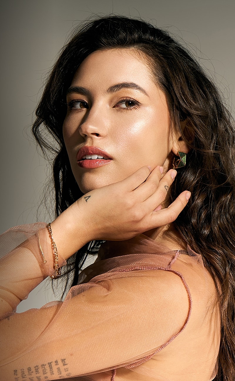 Woman with long hair and jewelry, elegant pose.