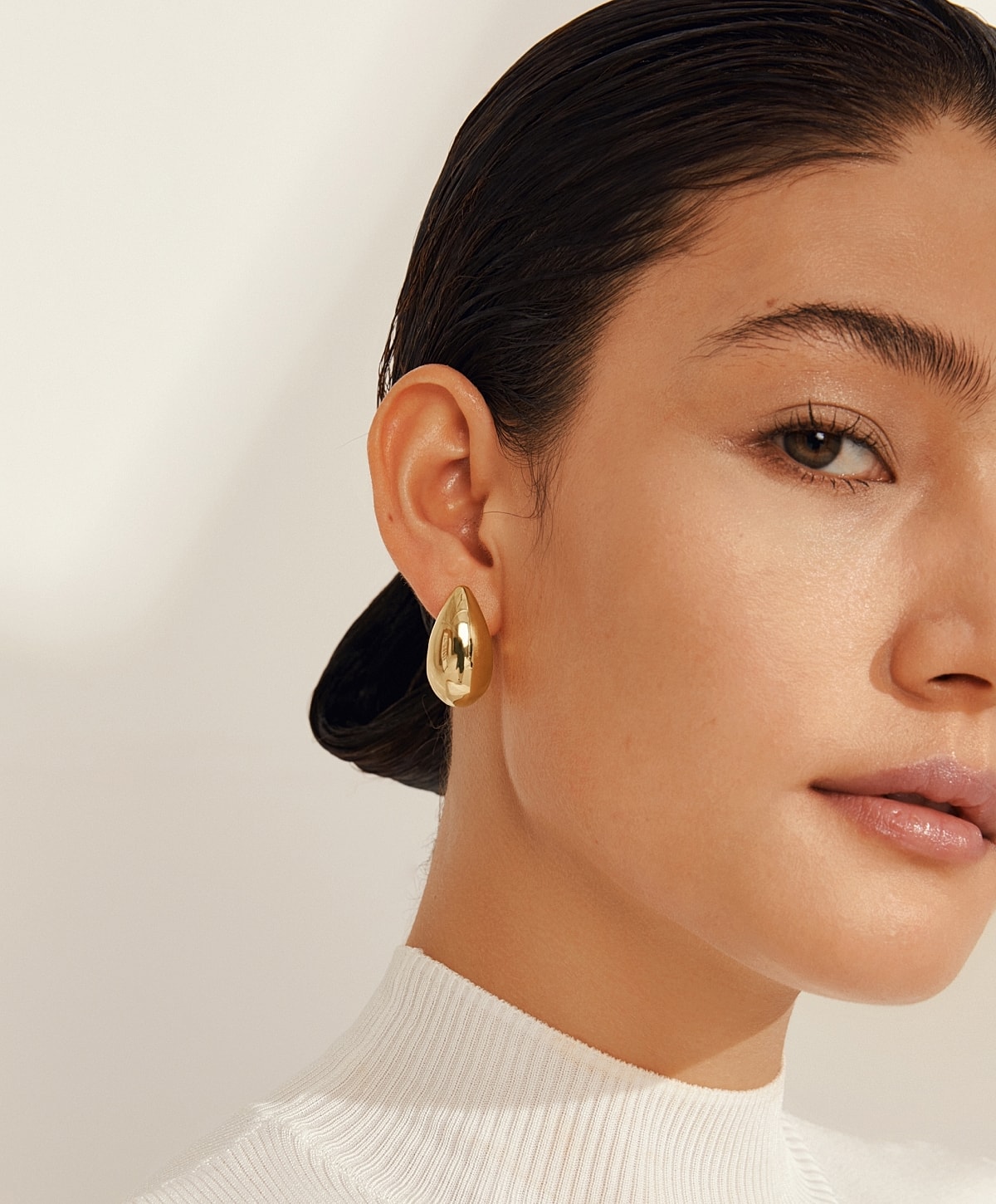 Model showcasing elegant gold earrings and hairstyle.