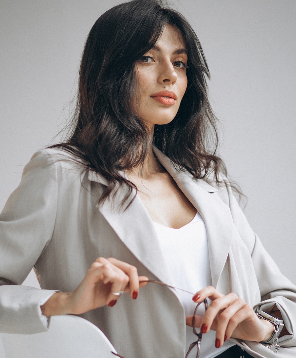Woman in a stylish outfit holding sunglasses.
