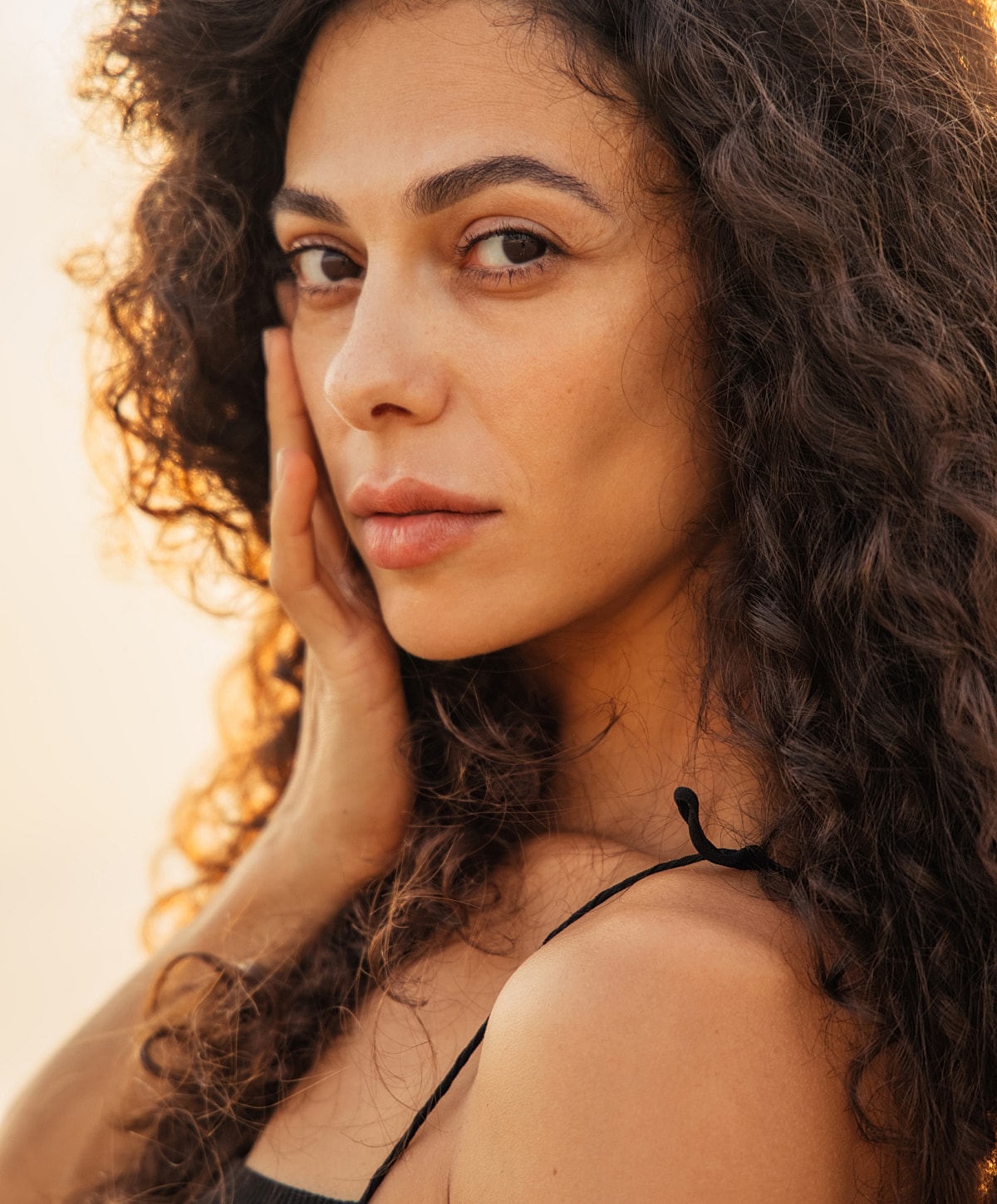 Woman with curly hair in soft lighting.