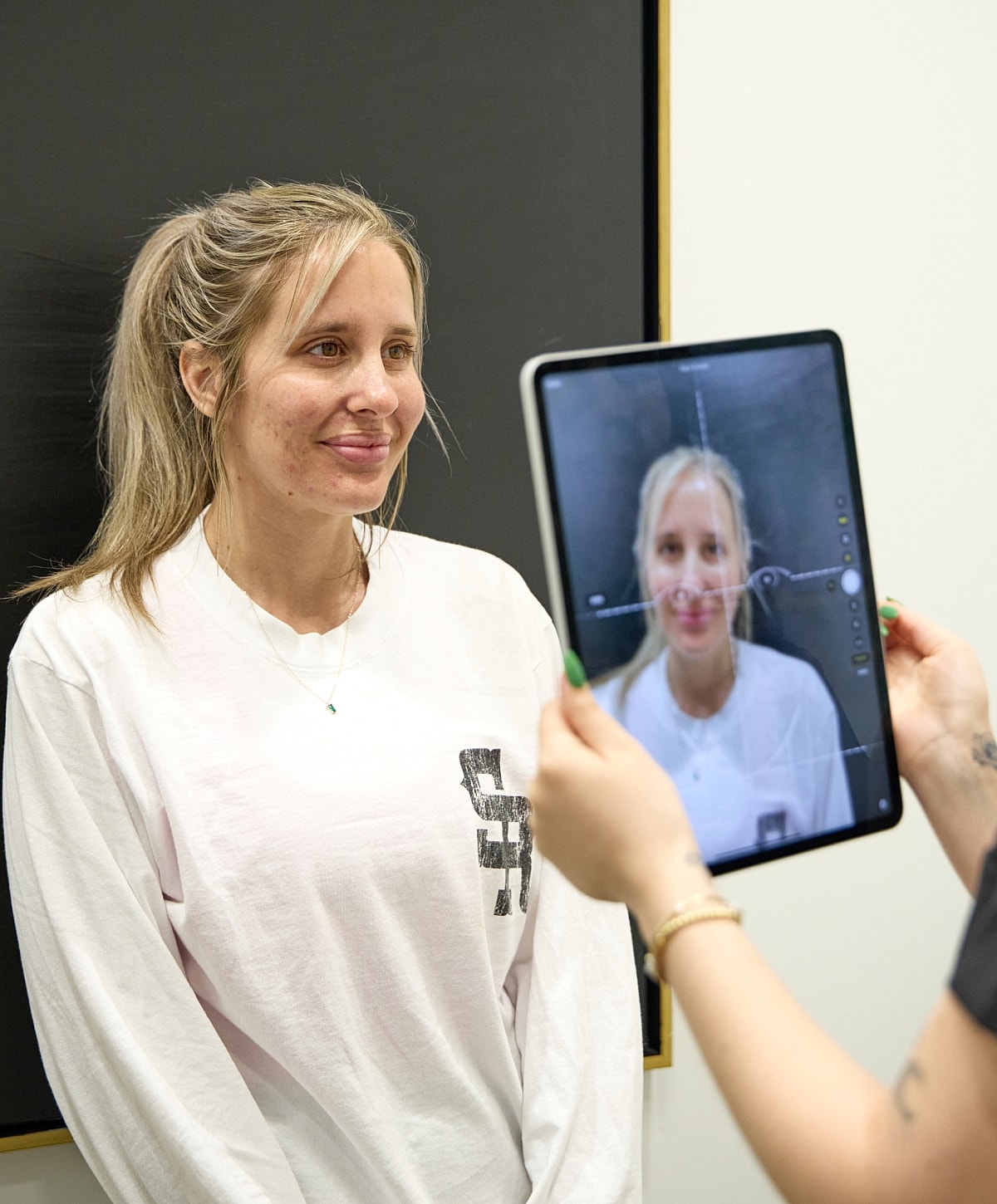 Woman smiling while being photographed with tablet.