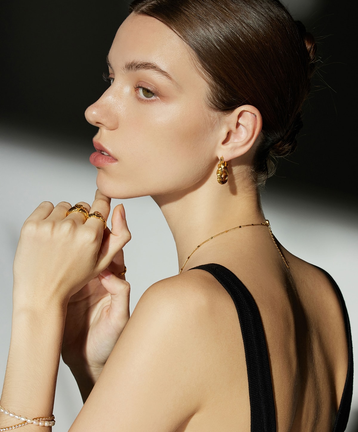 Model showcasing elegant golden jewelry and hairstyle.