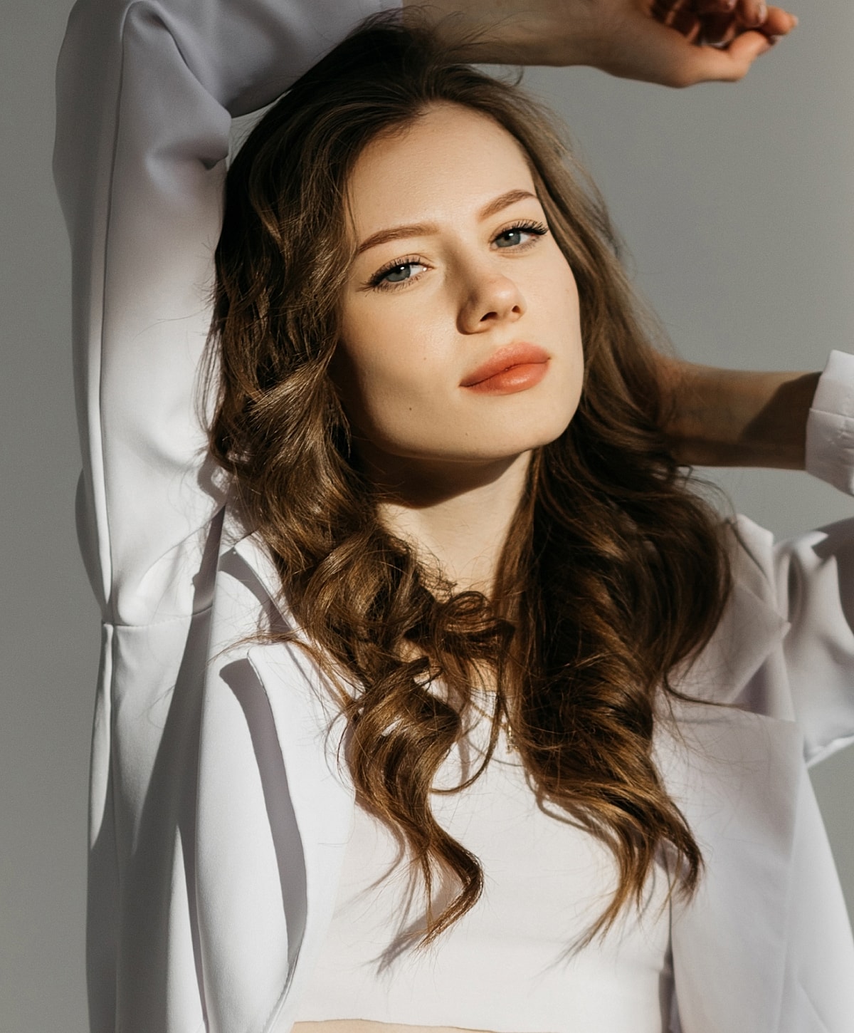 Young woman with wavy hair and neutral expression.