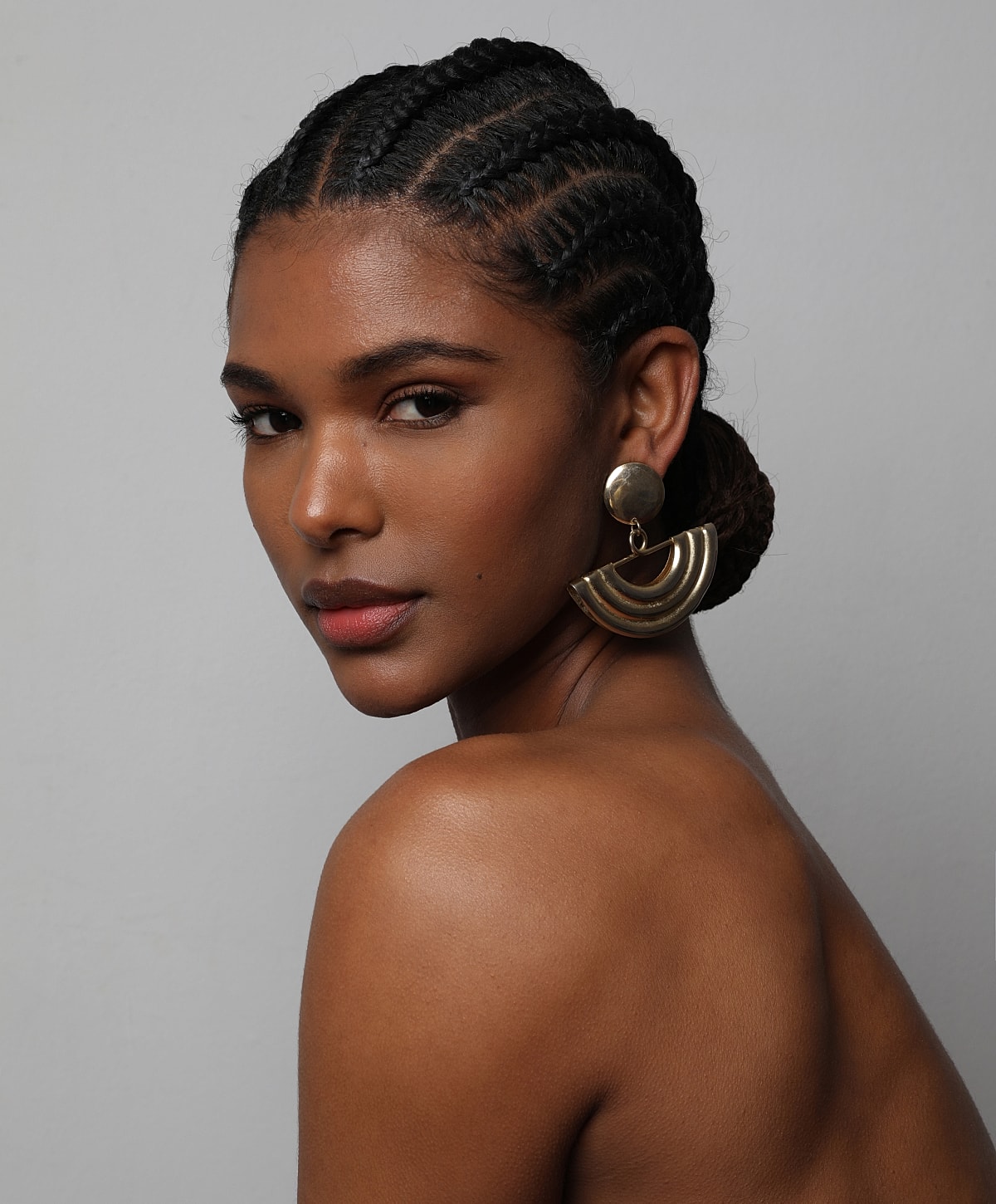Portrait of a woman with braided hair and earrings.