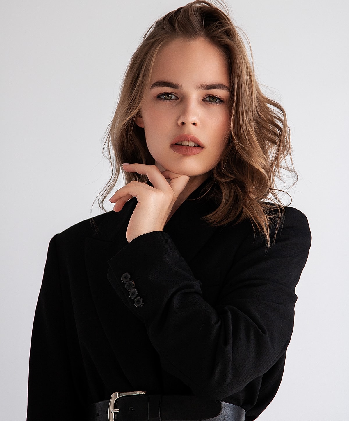 Woman in black blazer posing confidently indoors.