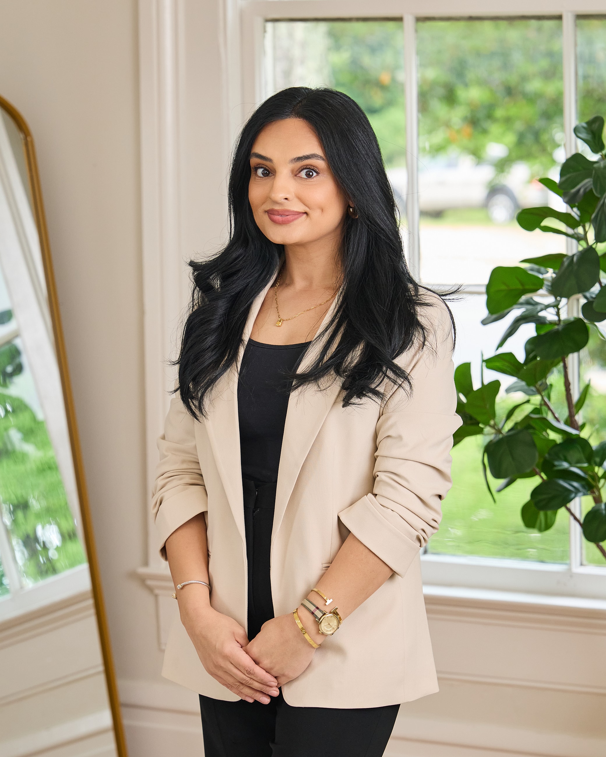 Woman in a beige blazer standing indoors.