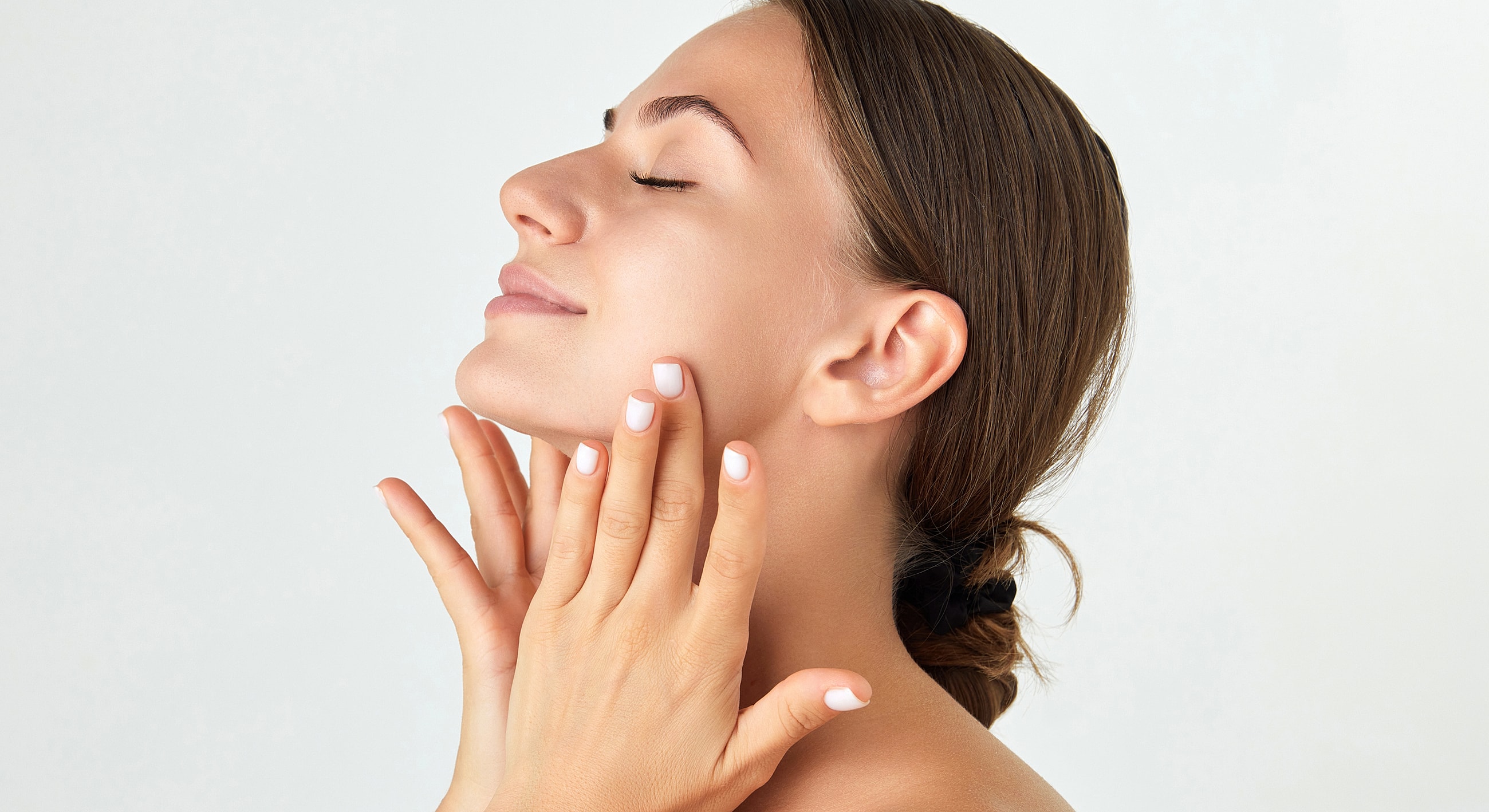 Woman gently touching her face and smiling.
