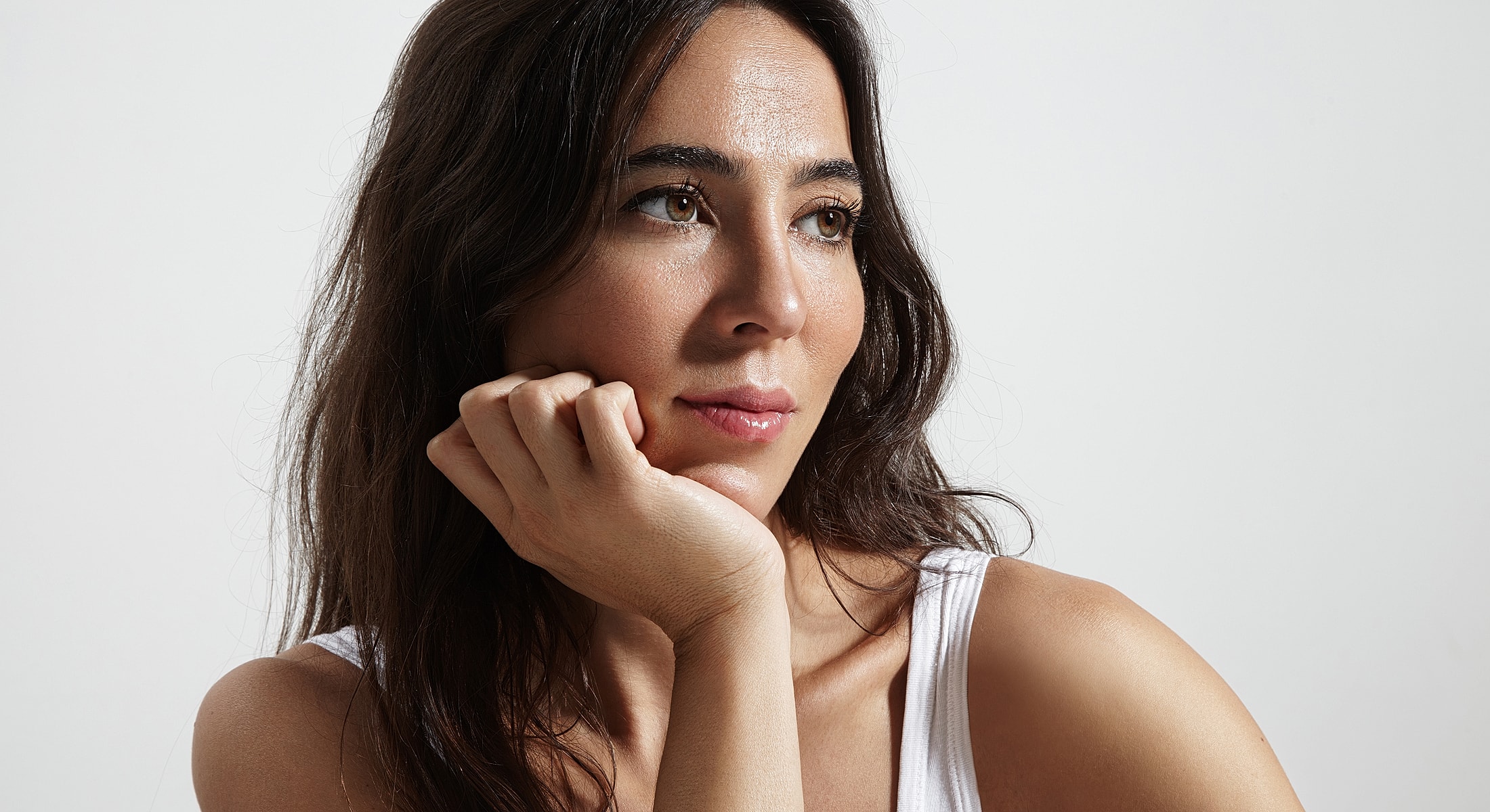 Woman resting chin on hand, thoughtful expression.