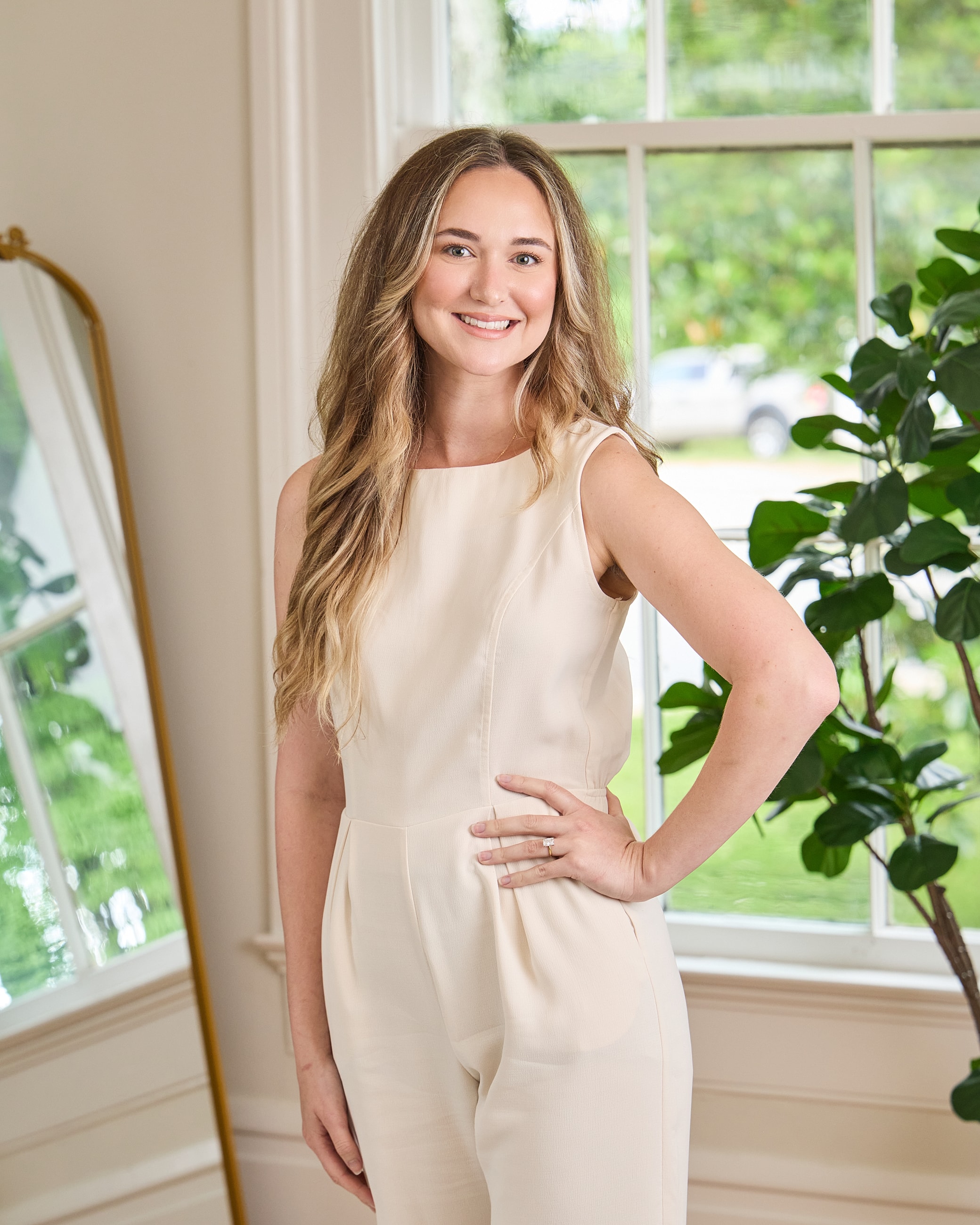 Smiling woman in a stylish cream jumpsuit.