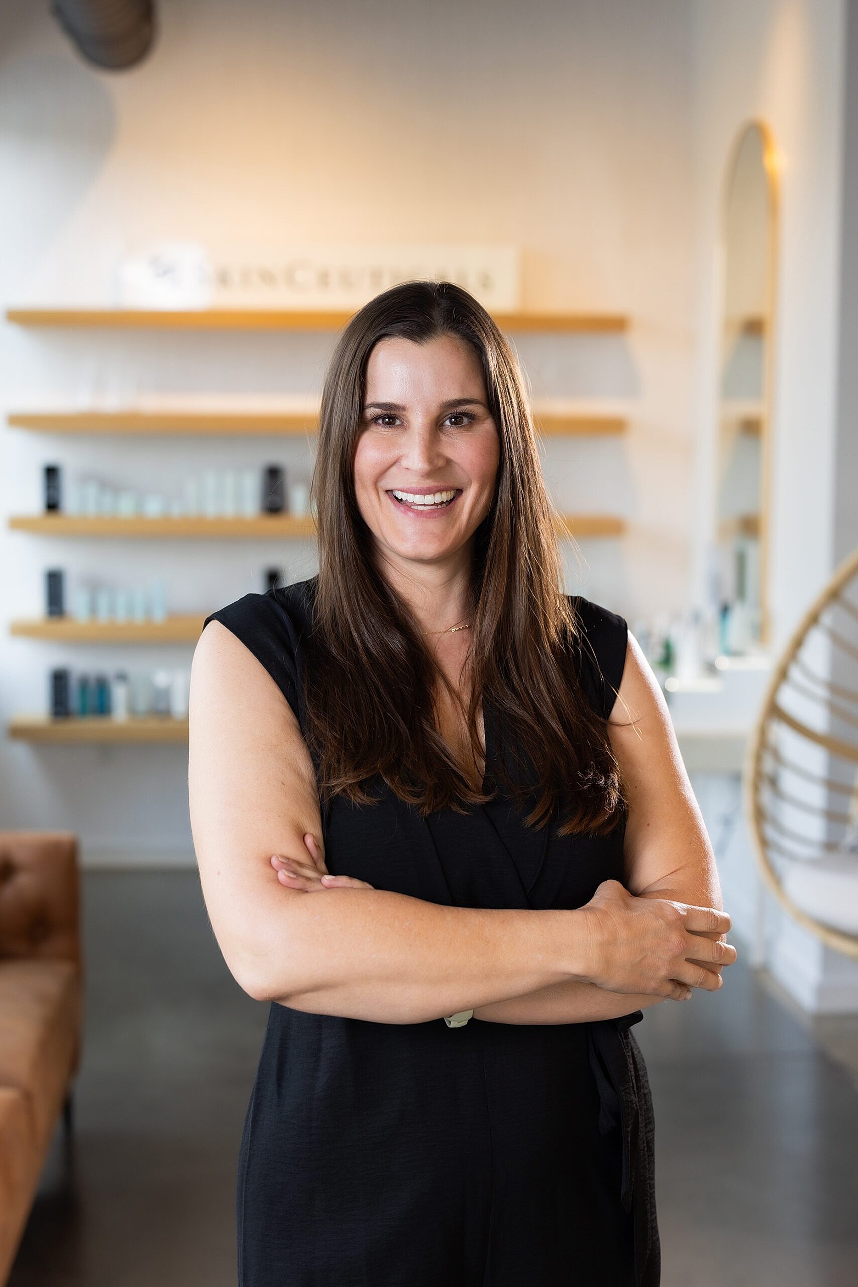 Smiling woman in professional setting, arms crossed.